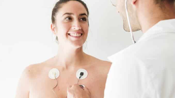 doctor with stethoscope near woman with electrodes