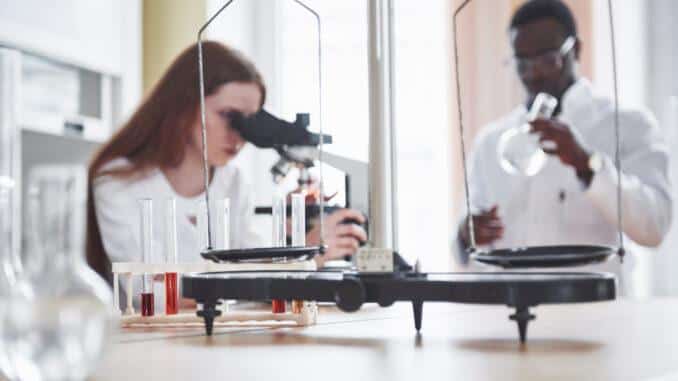 lab assistant with microscope laboratory glassware bulb with chemicals