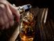 pouring strong alcohol drink into glasses which are wooden table
