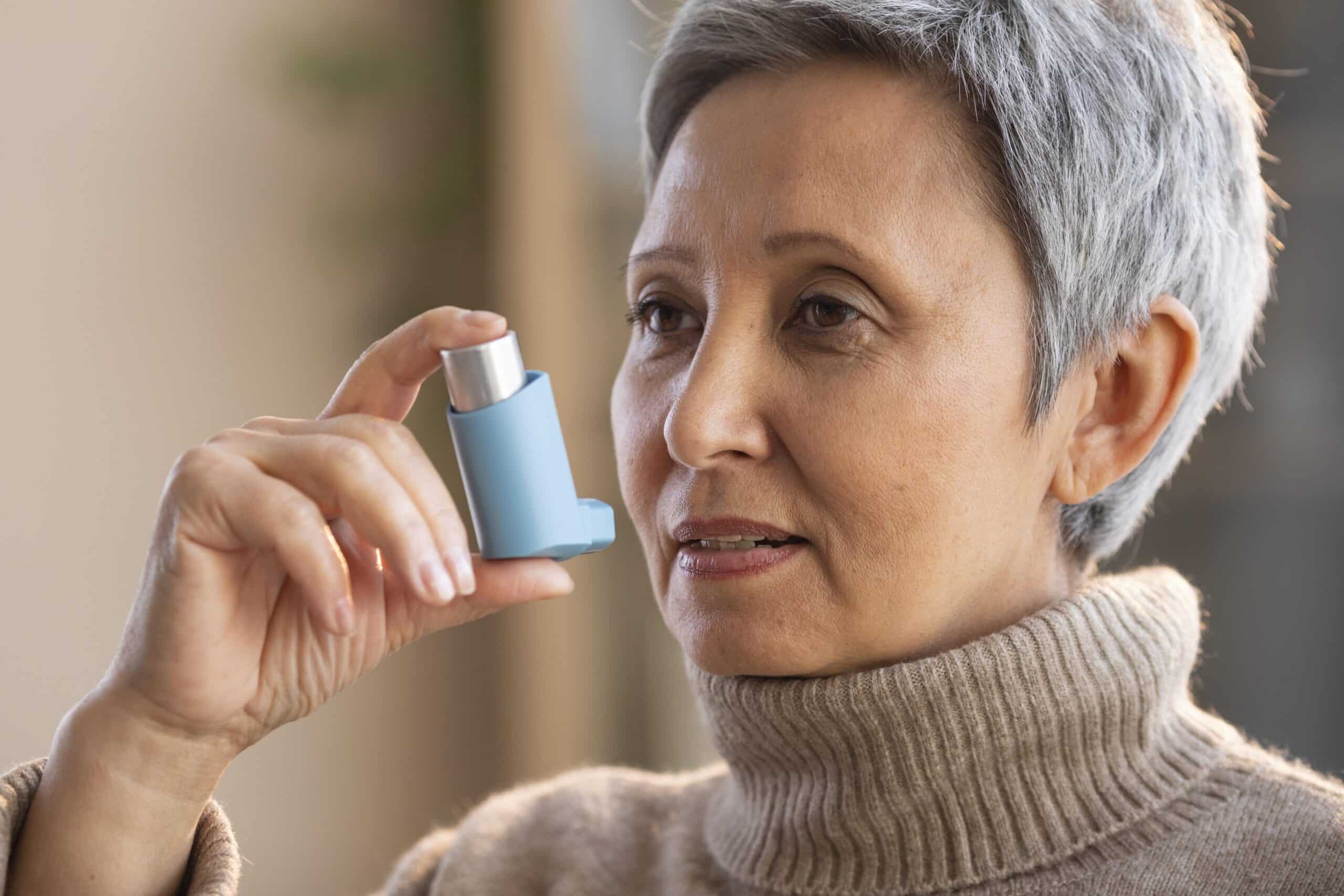 senior woman holding asthma inhaler scaled